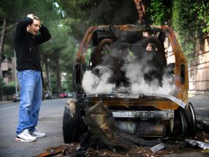 burnt down car and man in shock