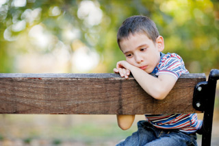Sad boy sitting on banch