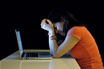 Woman crying sitting in front of a laptop, perhaps on social media