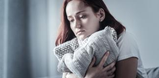 Sad woman hugging pillow | emotional pain