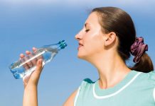 beautiful woman drinks water on a blue sky