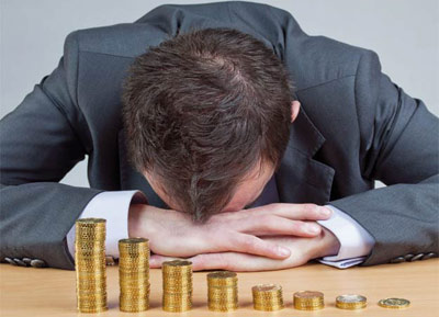 Man with his head down in front of coins