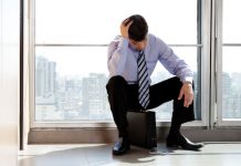 Hit a plateau in your career? Here’s what you can do Tensed man in tie sitting on his breifcase with his hand on his head, frustrated in career