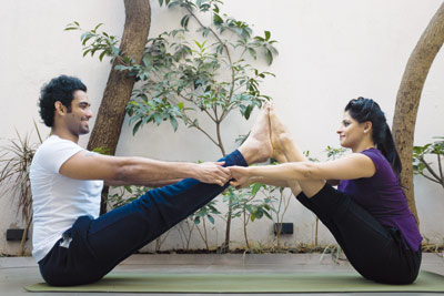 Couple doing the boat pose of yoga