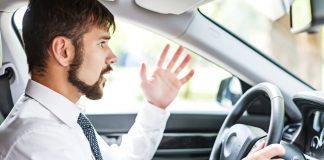 man wearing a tie is frustrated driving car, seems to be complaining