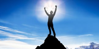 The Point of Struggle Silhouette of a victorious man on top of a mountain