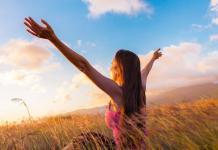 Girl raising arms towards beautiful glowing sunshine / emptiness and love