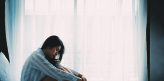 Contemplative woman sitting alone on a bed | Concept of vulnerability