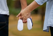 couple holding hands with baby shoes, fertility