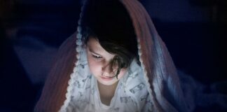 Overexposure to screens may hasten puberty arrival child staring at a mobile device in the dark