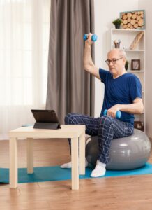 Senior man doing dumbbell workout sitting on an exercise ball