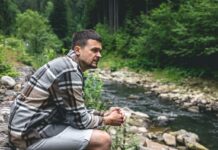 Man sitting alone in the woods watching the stream | wisdom seeker