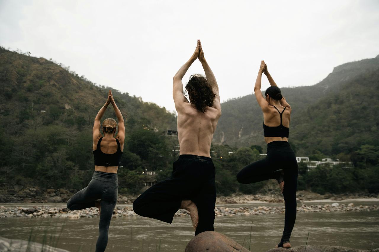 Group of yogis standing in the tree pose outdoors 