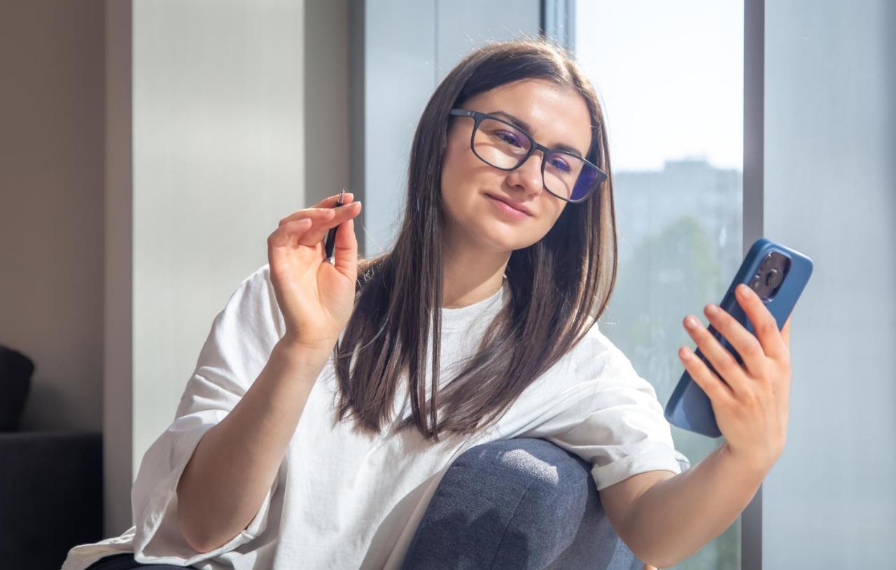 Woman looking at her phone screen wearing blue light glasses