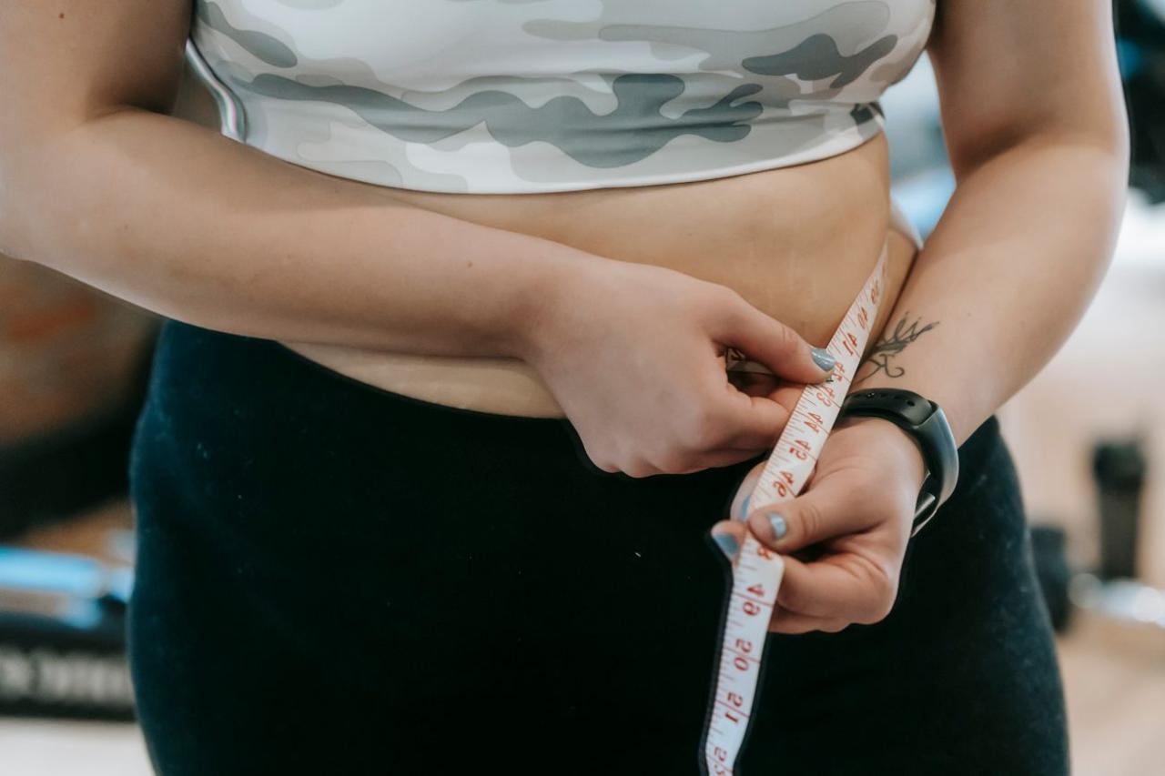 Close of woman measuring her waist with a tape